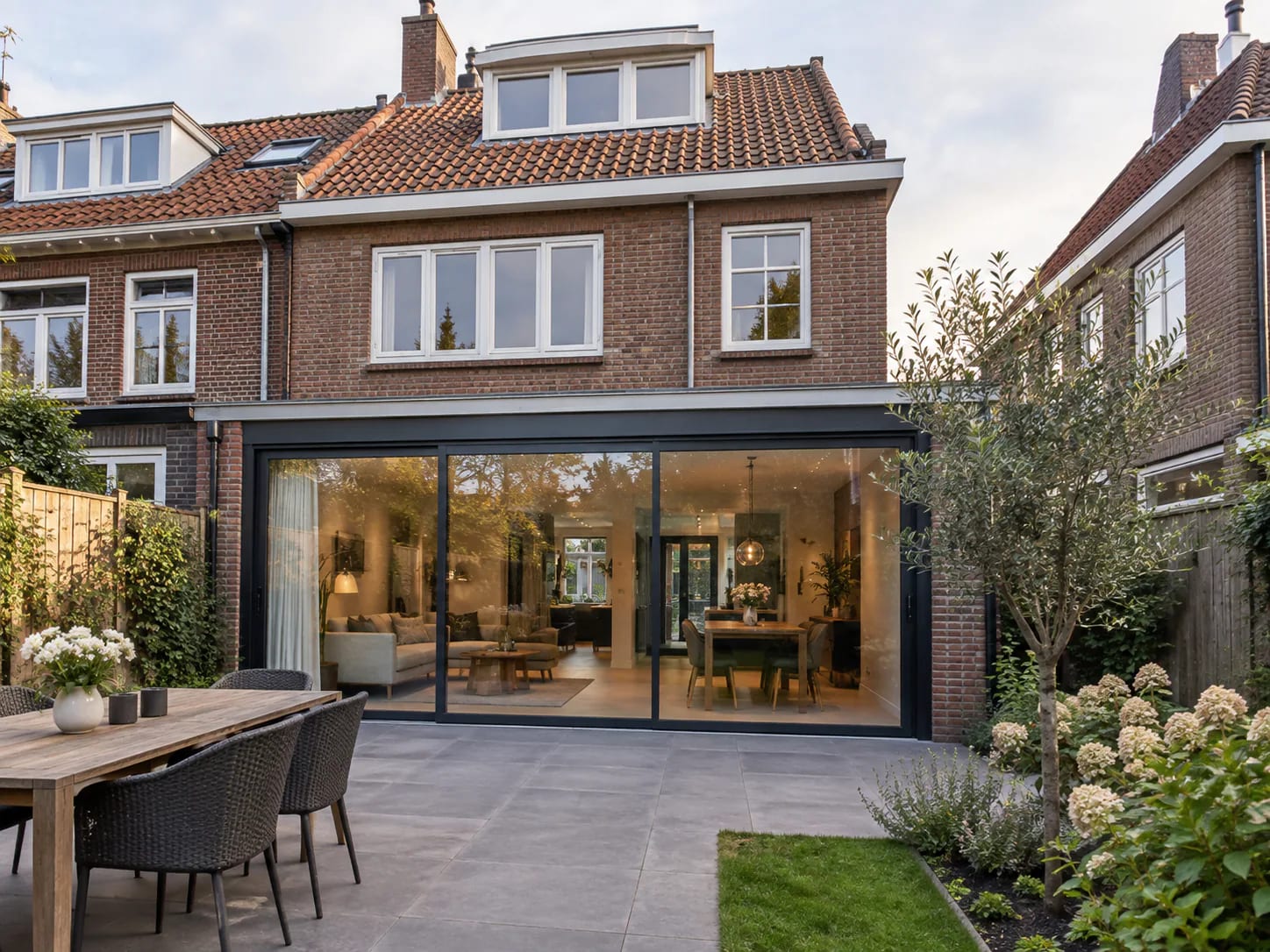 Grote driedelige glaspui in een bakstenen achtergevel, met zicht op woonkamer en terras