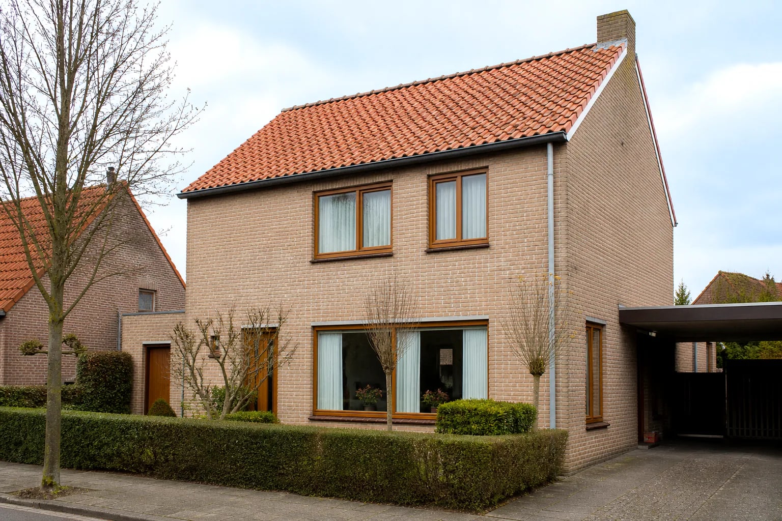 Vrijstaande Nederlandse gezinswoning met warme houten kozijnen in een lichte baksteengevel